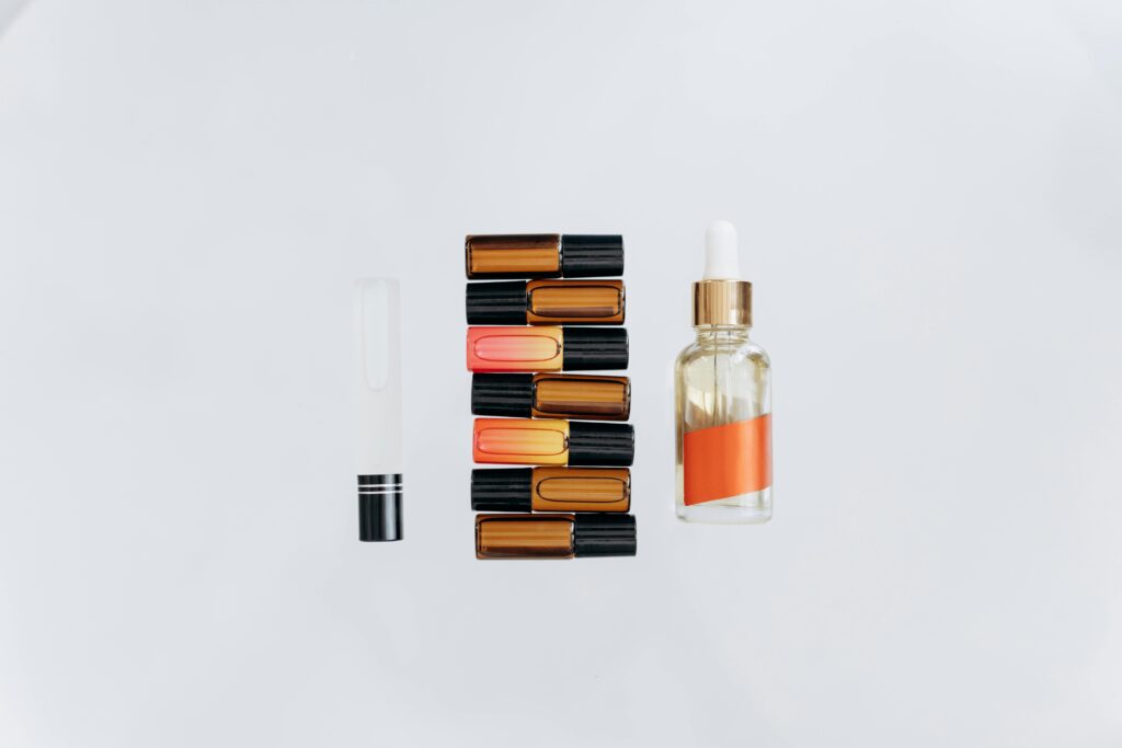 Stylish arrangement of essential oils and lipsticks on a white background, perfect for beauty and wellness themes.