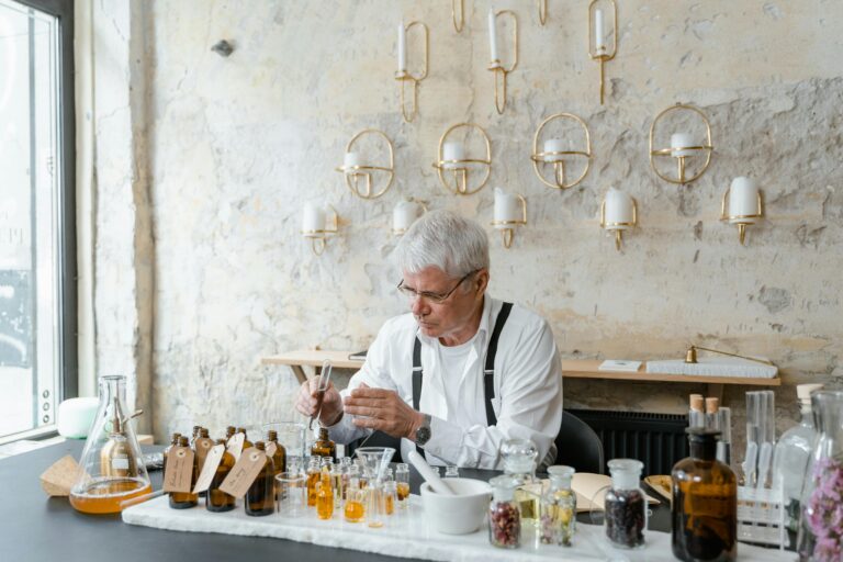 Senior perfumer blends fragrant ingredients in stylish indoor setting.